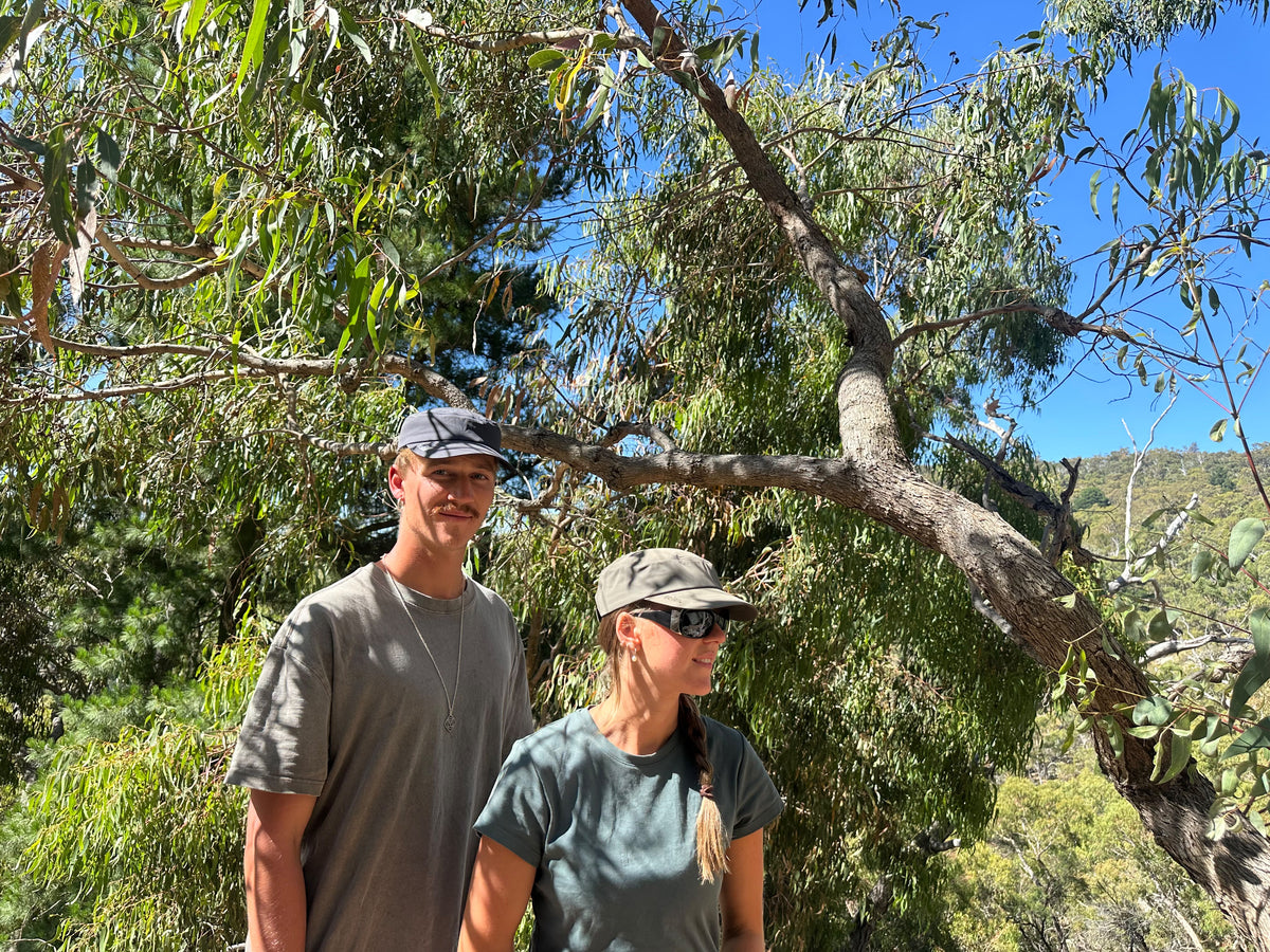 Two friends in the bush wearing the Archive Army Cap in grey blue and khaki green